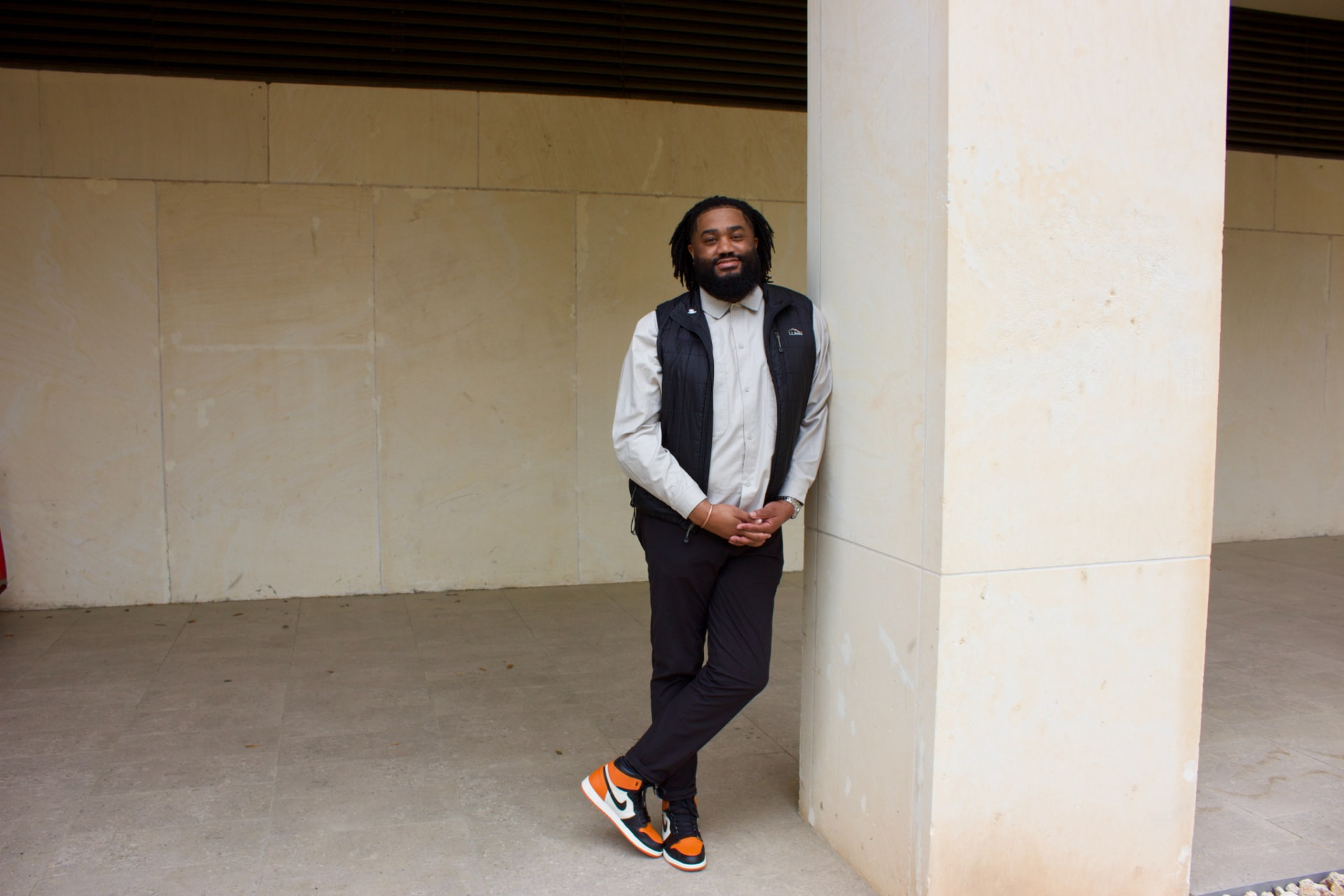 Jerold McDonald leaning against a light stone column
